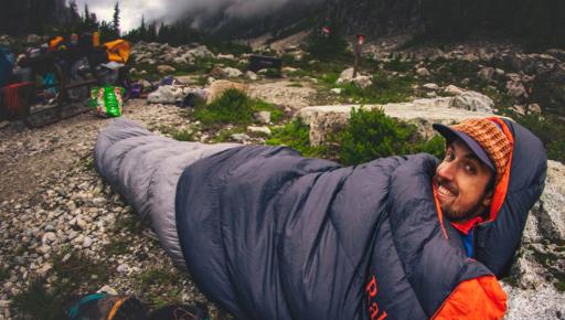 man in slaapzak van rab in de bergen